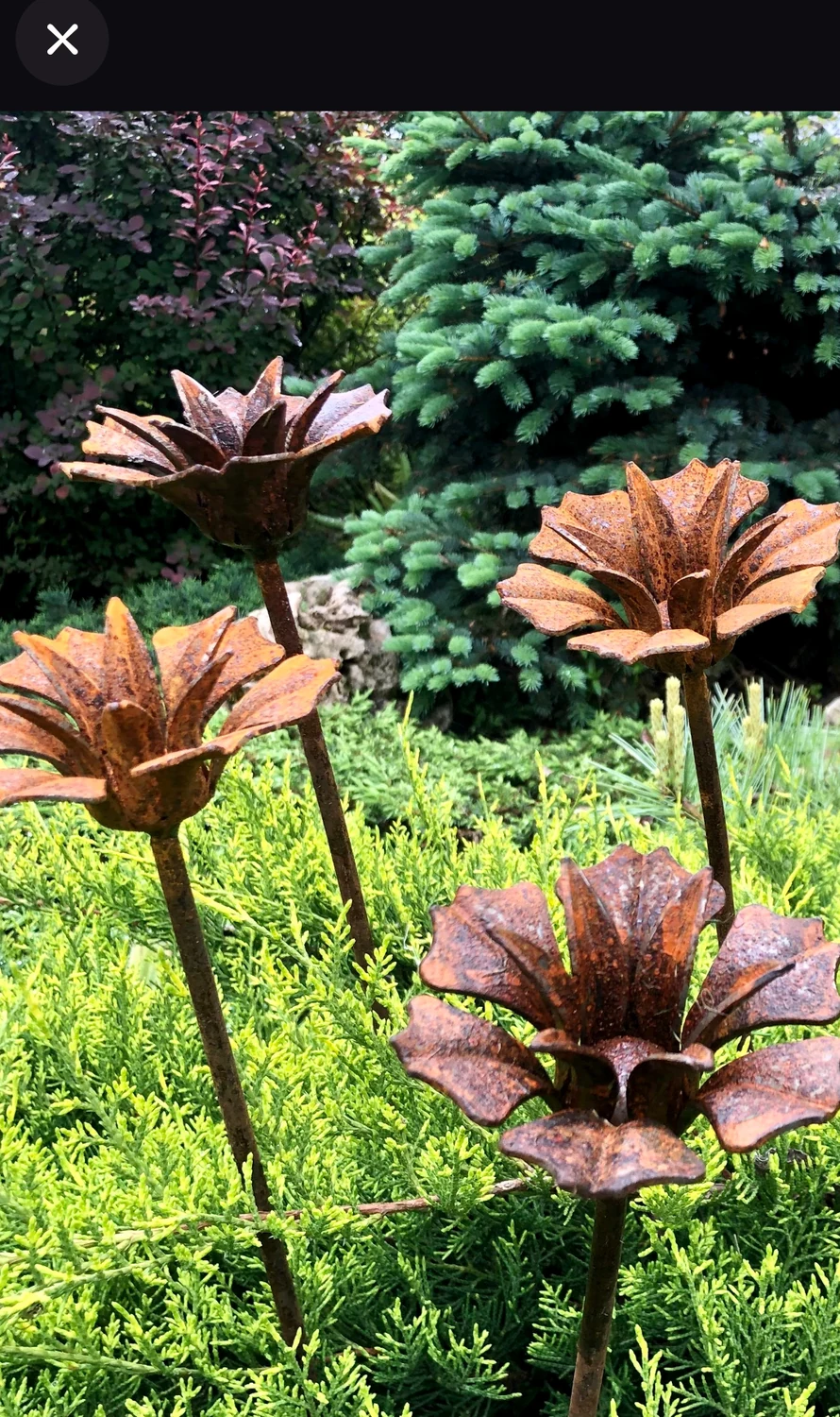 Layered rust-toned metal flowers in a garden